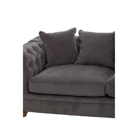 Three-seat grey fabric sofa featuring a tufted design on the armrest and back, with two plush cushions for added comfort. The sofa has wooden legs and a modern aesthetic suitable for various home decor styles