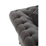 Grey fabric sofa with a tufted design, featuring a plush seat and armrest. The corner of the sofa shows a soft texture and rounded edges, highlighting its modern style