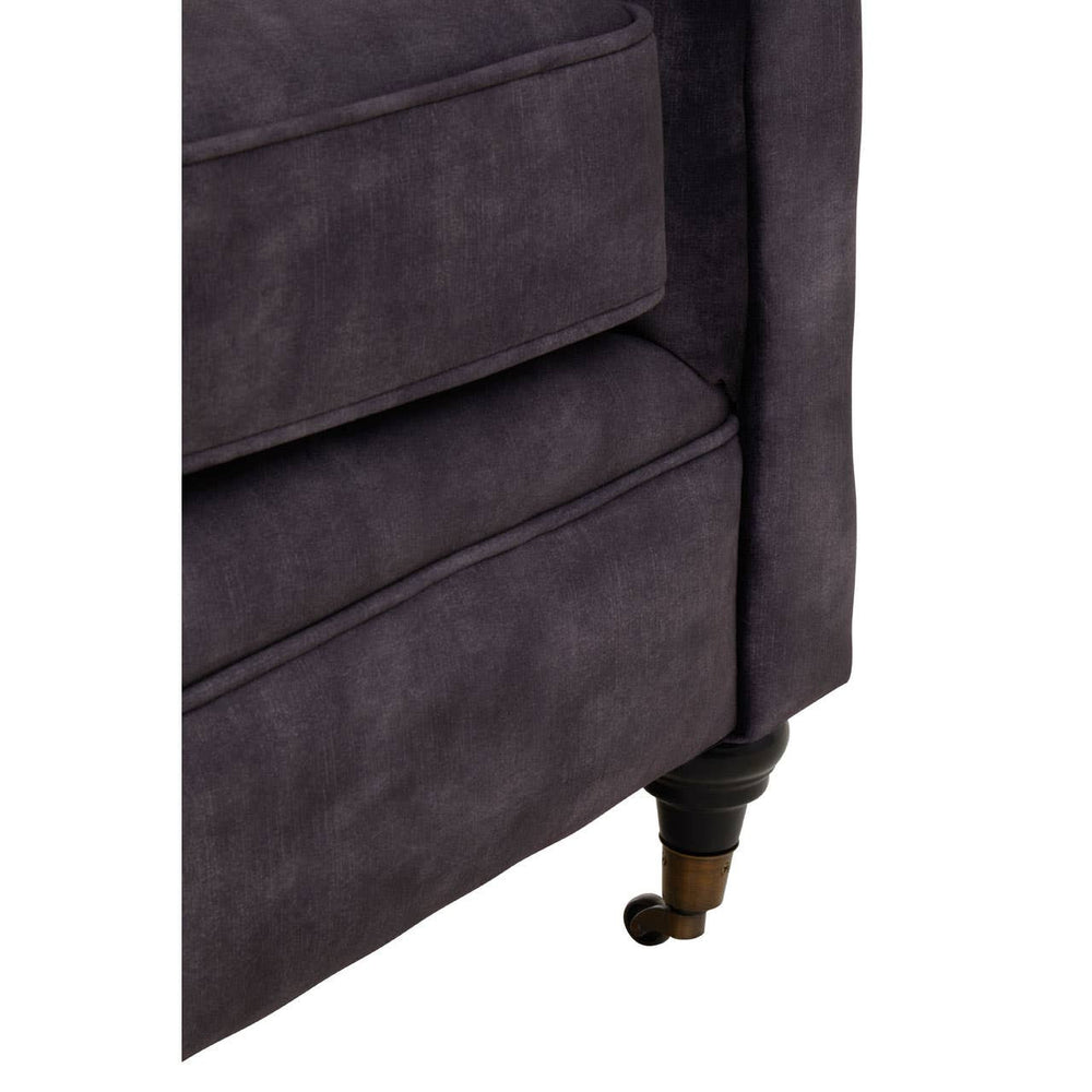 Close-up view of the corner of a two-seat sofa upholstered in grey velvet, featuring a sleek design with a slightly curved armrest and elegant wooden legs. The texture of the fabric is soft and plush, highlighting its luxurious appearance
