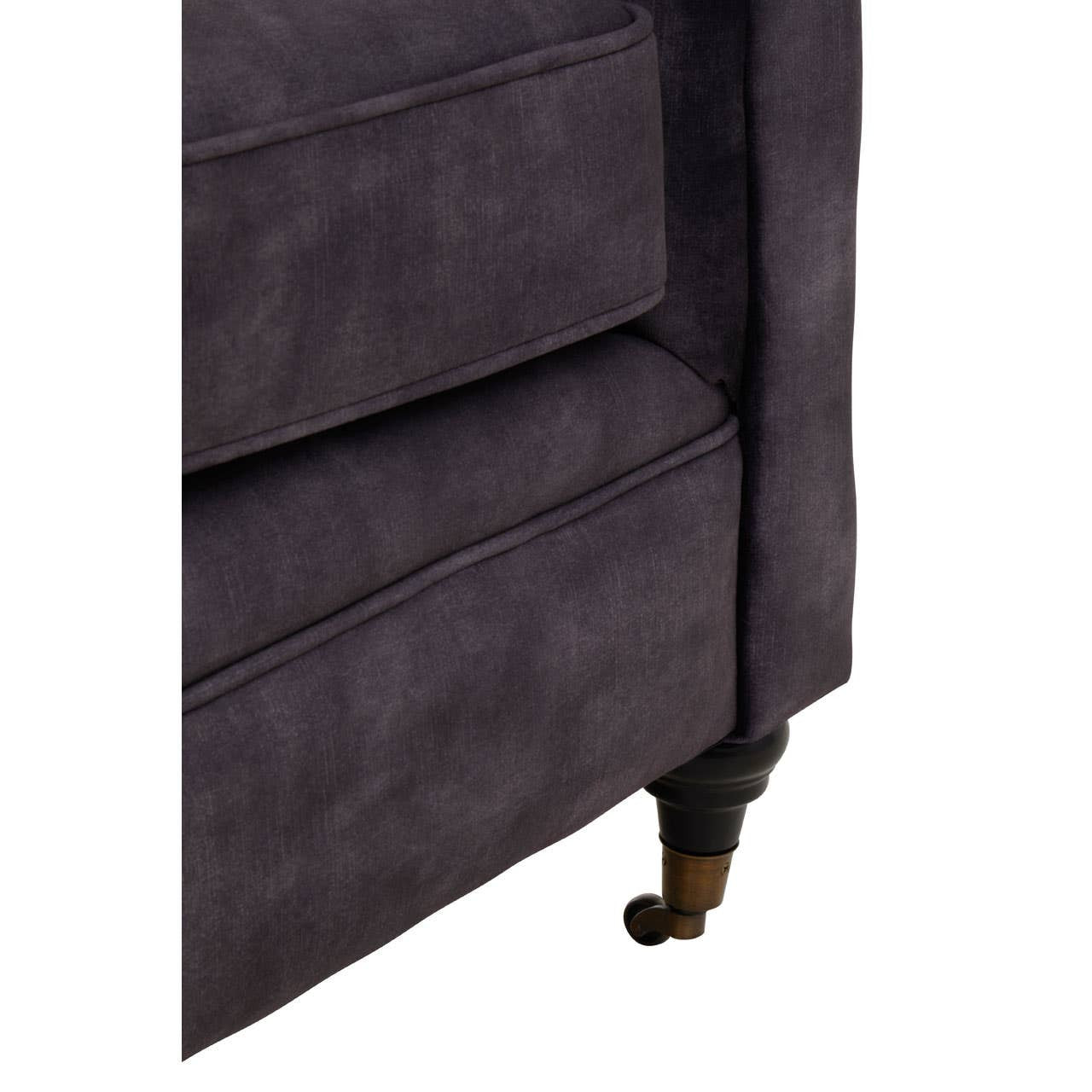 Close-up view of the corner of a two-seat sofa upholstered in grey velvet, featuring a sleek design with a slightly curved armrest and elegant wooden legs. The texture of the fabric is soft and plush, highlighting its luxurious appearance