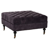 Dark grey velvet ottoman with deep button tufting and turned wooden legs on castors