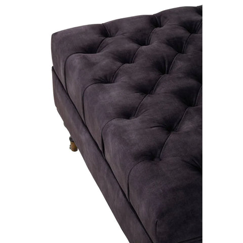 Dark grey tufted fabric ottoman with wooden feet, close-up of cushioned top