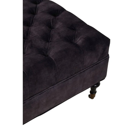 Plush dark velvet ottoman with button tufted upholstery and black turned wooden leg
