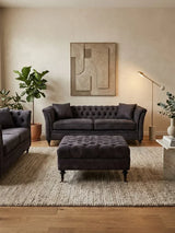 Dark grey velvet sofa set with matching ottoman on textured rug in modern living room