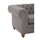 Grey linen sofa with a tufted backrest and rolled arms, featuring wooden legs. The corner of the sofa is visible, showcasing its elegant design and soft fabric texture