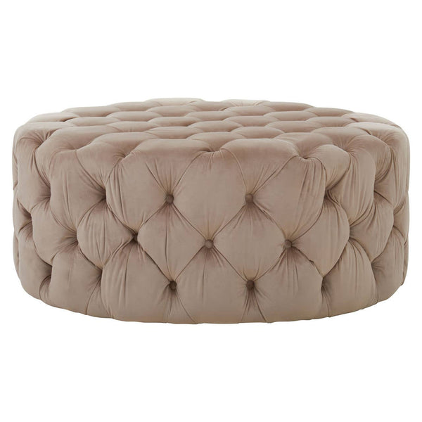 Beige velvet round ottoman stool with a tufted design, featuring a soft, plush surface and a circular shape, suitable for use as a footrest or additional seating