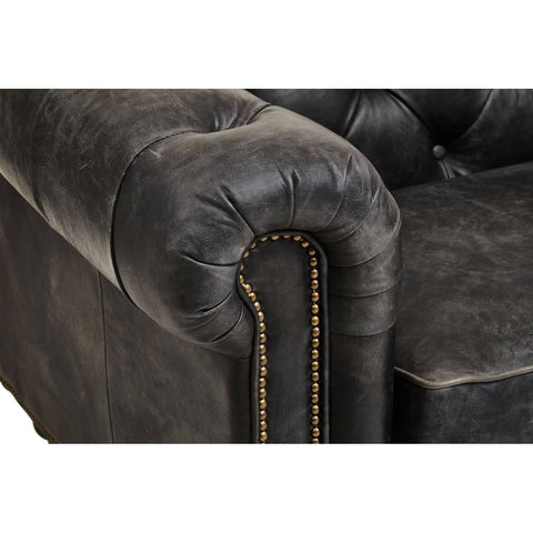 Antique black leather upholstery with a tufted design and rolled armrest, featuring decorative stitching along the seams. The sofa showcases a classic Chesterfield style with a luxurious and worn appearance, highlighting its vintage charm