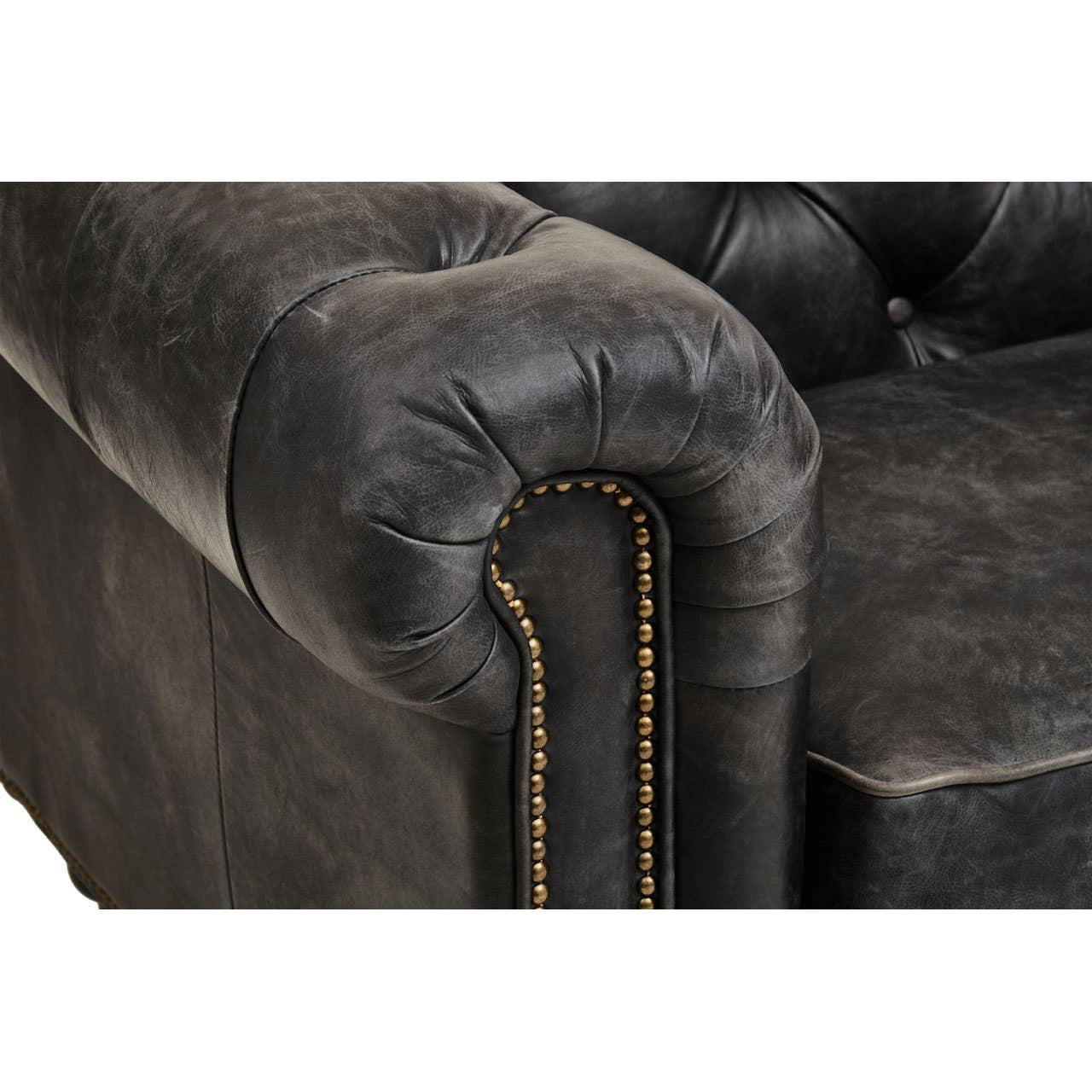 Antique black leather upholstery with a tufted design and rolled armrest, featuring decorative stitching along the seams. The sofa showcases a classic Chesterfield style with a luxurious and worn appearance, highlighting its vintage charm