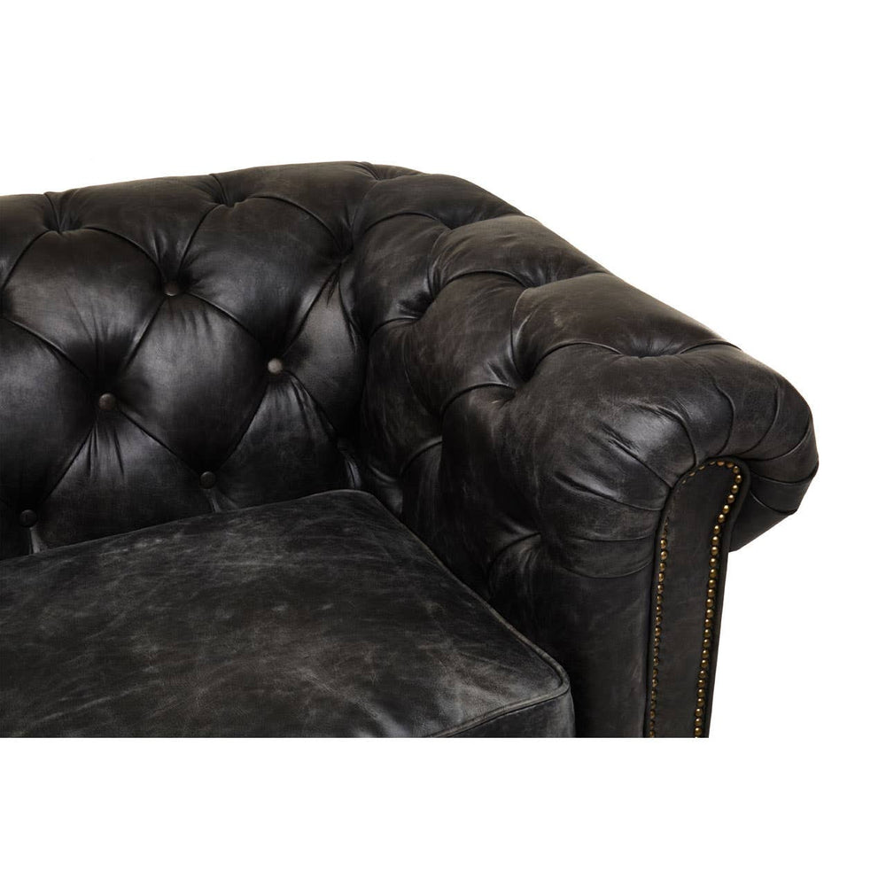 Antique black leather Chesterfield sofa featuring a tufted design on the armrest and back, showcasing a classic and elegant style. The leather has a distressed finish, adding character to the piece