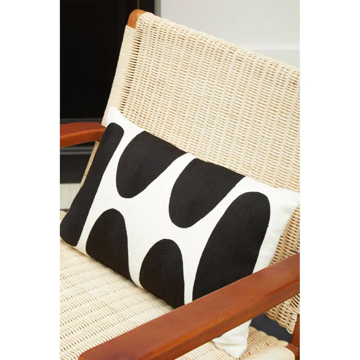 Woven lounge chair with black and white geometric cushion on seat