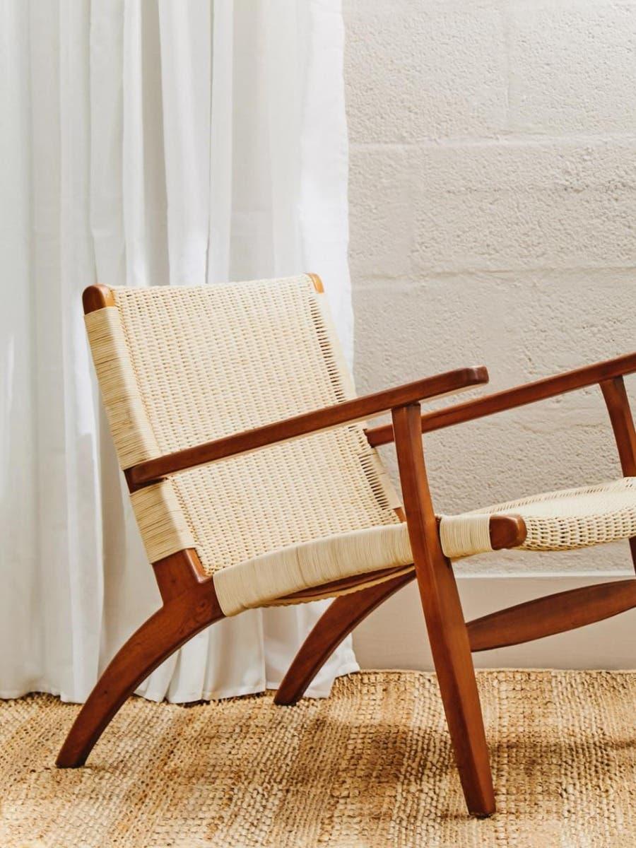 Mid-century accent chair with woven rattan seat and teak wood frame on textured rug
