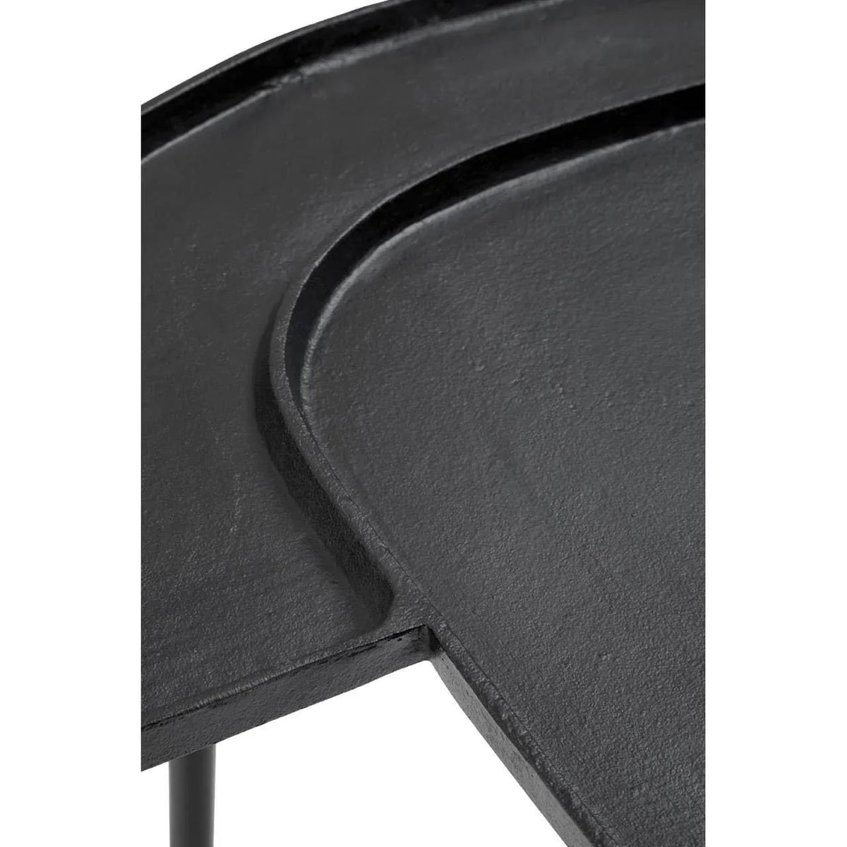 Close detail of black metal side table top with curved edge and textured finish