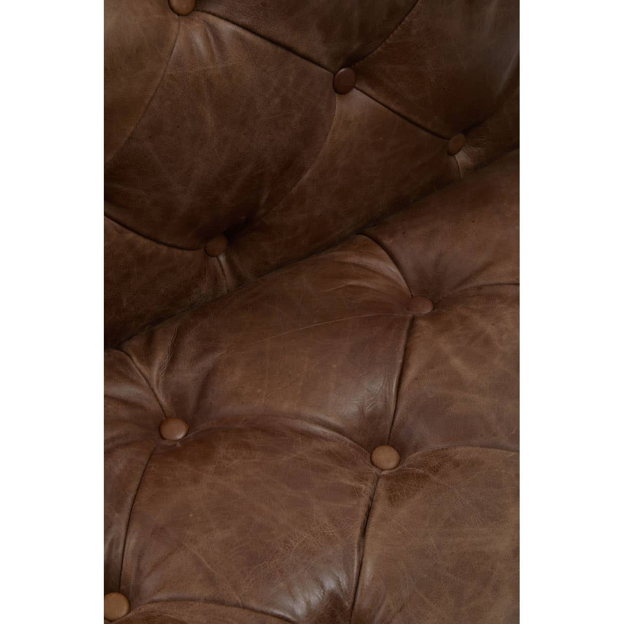 Close-up view of a brown leather Chesterfield sofa chair featuring a tufted design with visible stitching and buttons, showcasing the rich texture and color of the leather
