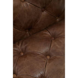 Close-up view of a brown leather Chesterfield sofa chair featuring a tufted design with visible stitching and buttons, showcasing the rich texture and color of the leather