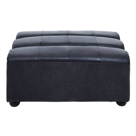 Antique black leather modular ottoman with a tufted top and rounded edges, featuring a sturdy base and small, round feet