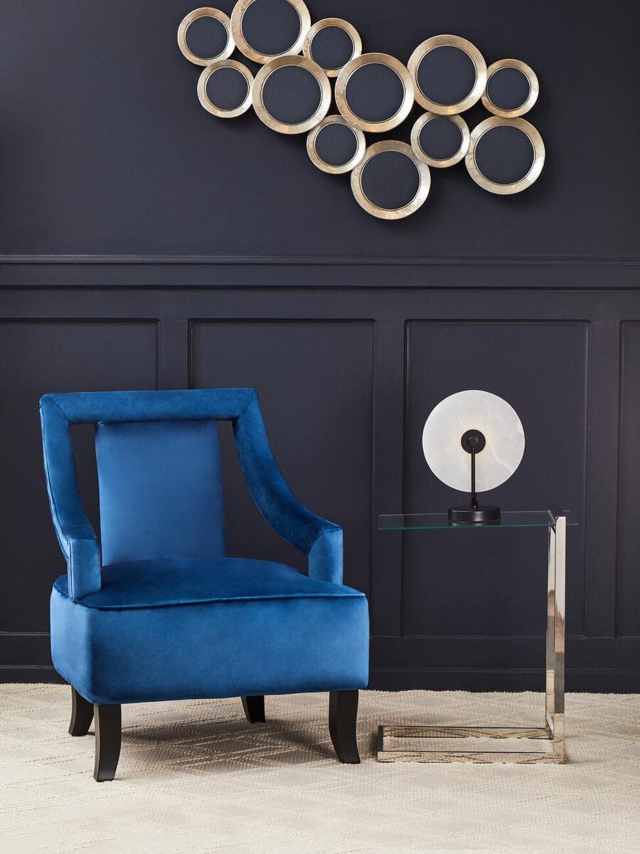 Blue velvet accent chair with black legs beside glass side table in modern living room