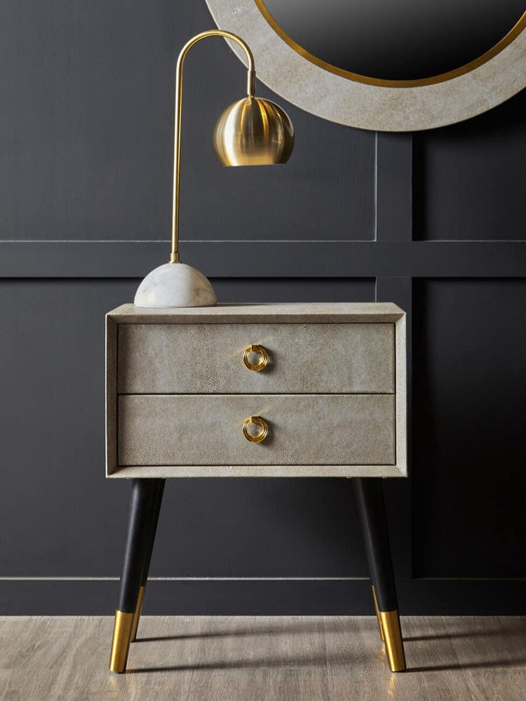 Modern bedside table with gold handles, black and gold legs, and gold table lamp