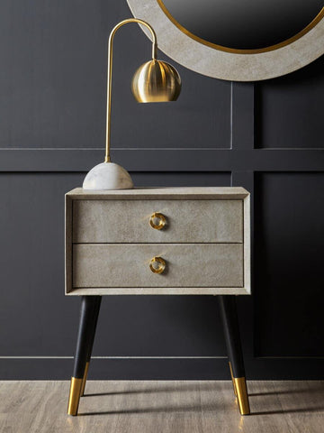 Modern bedside table with gold handles, black and gold legs, and gold table lamp