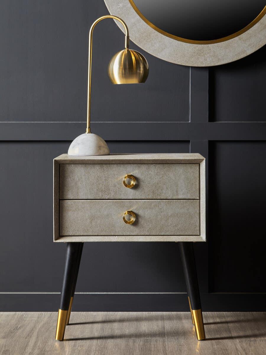 Modern bedside table with gold handles, black and gold legs, and gold table lamp