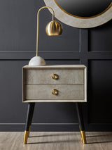 Modern bedside table with gold handles, black and gold legs, and gold table lamp