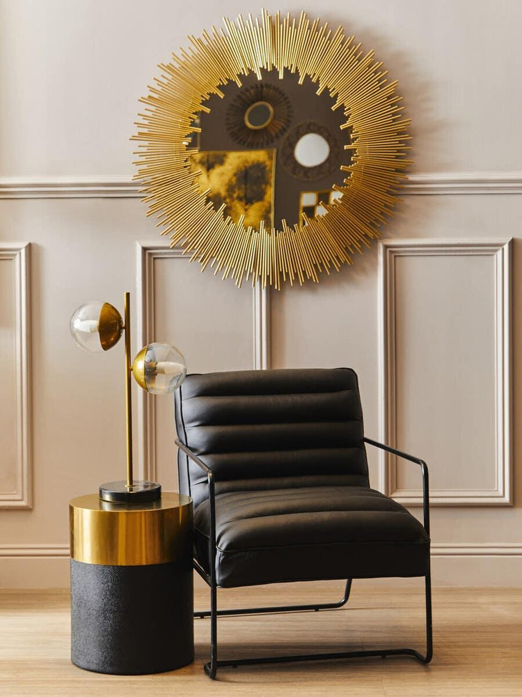 Black leather accent chair with gold side table and modern sunburst wall mirror