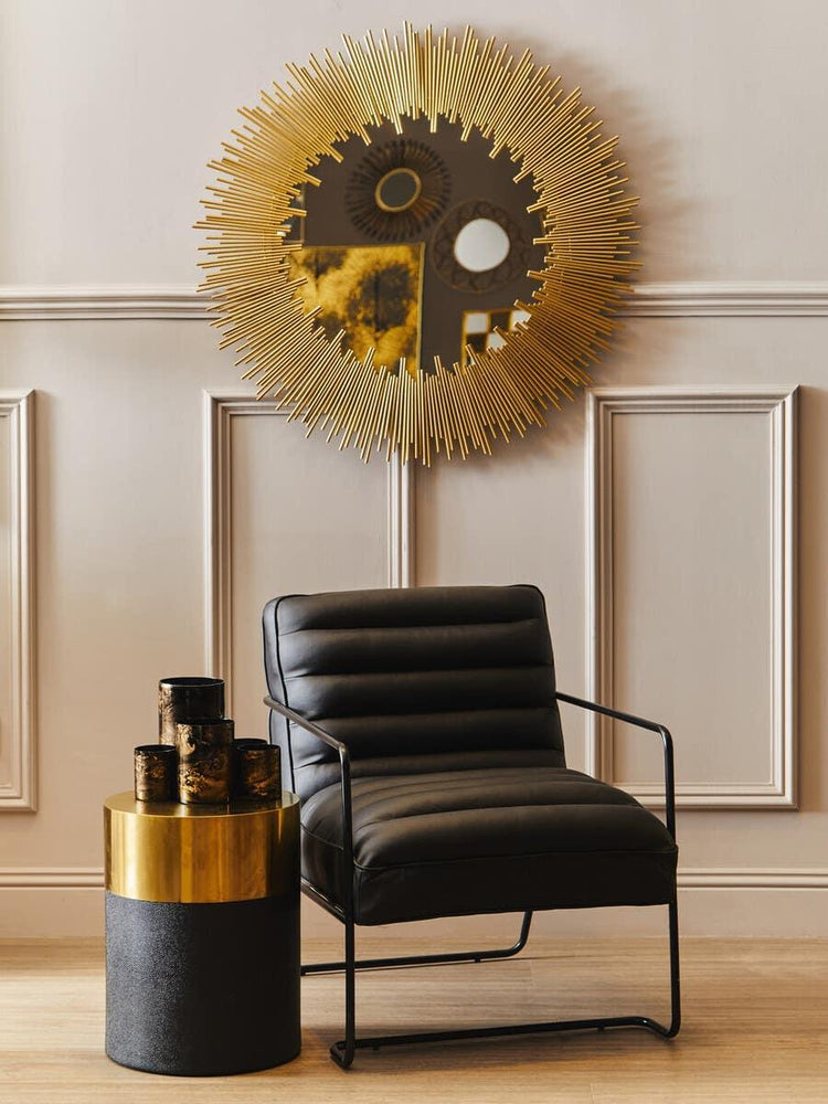 Black leather accent chair with gold side table and sunburst wall mirror in modern living room