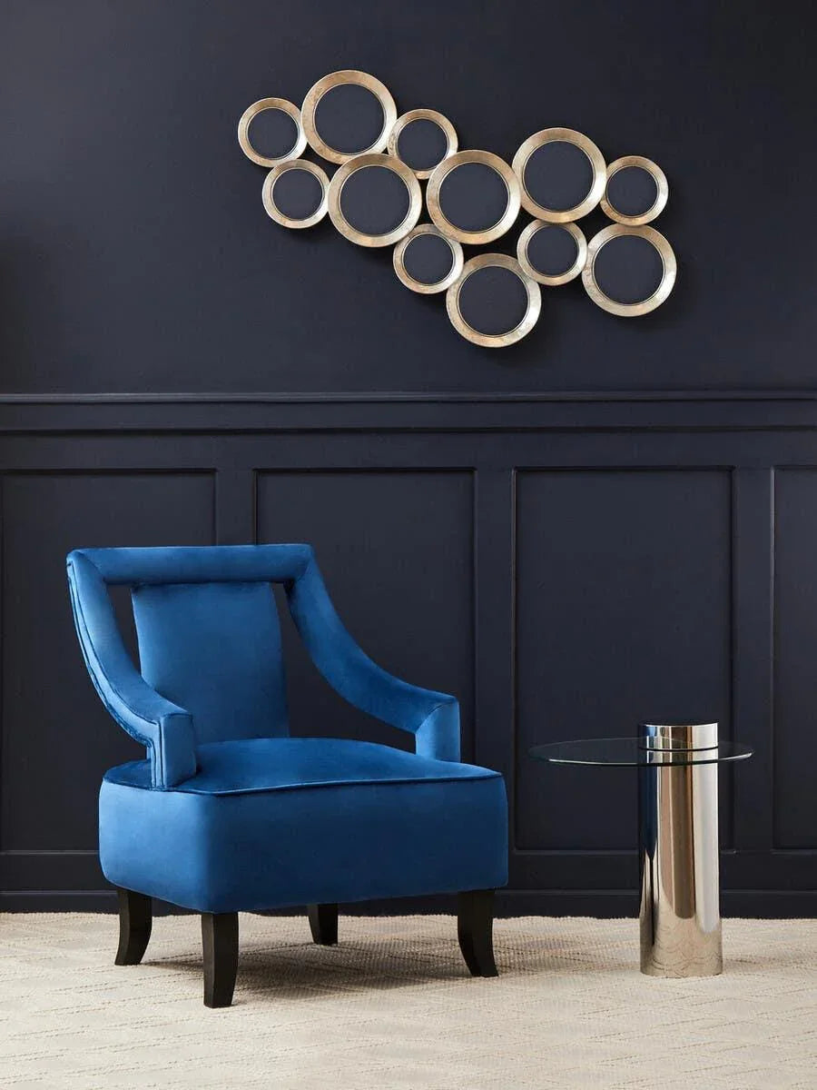 Blue velvet armchair with dark wood legs beside round glass side table on beige rug