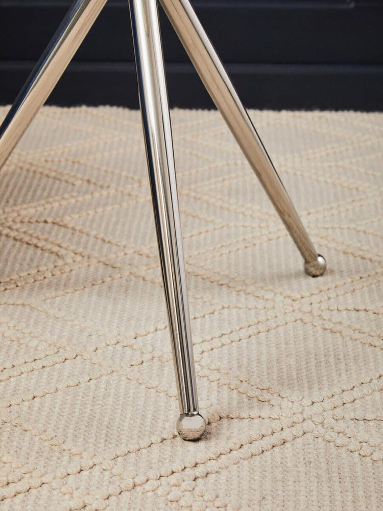 Chrome dining table legs on textured cream rug