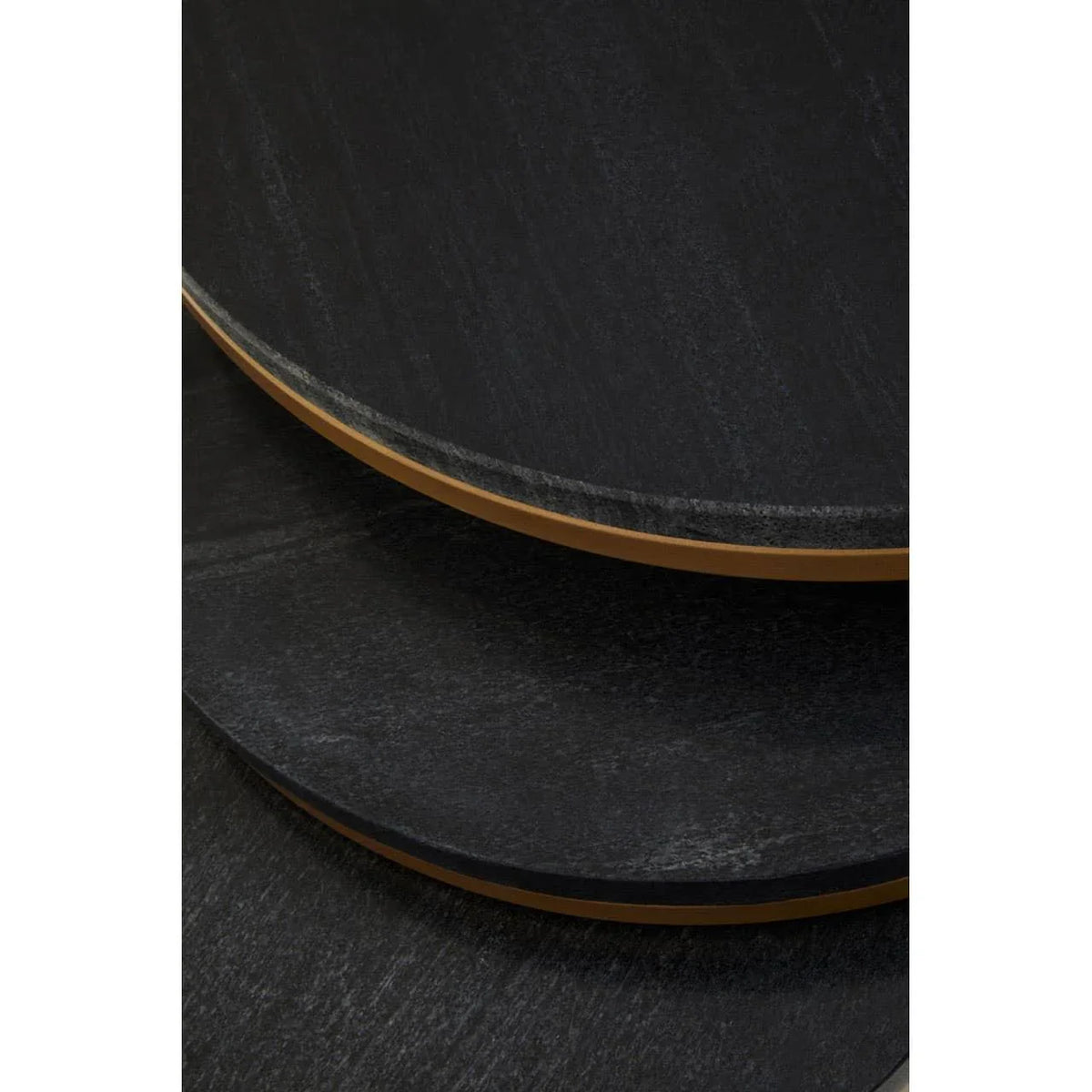 Close up of black round nesting coffee tables with gold trimmed edges