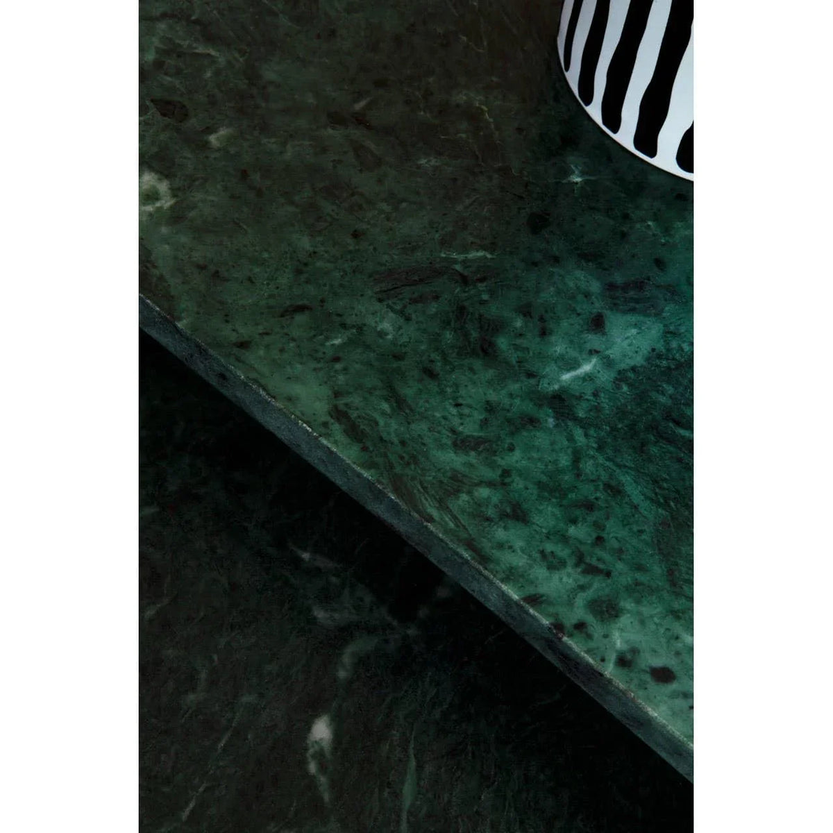 Green marble coffee table corner with striped vase detail on surface