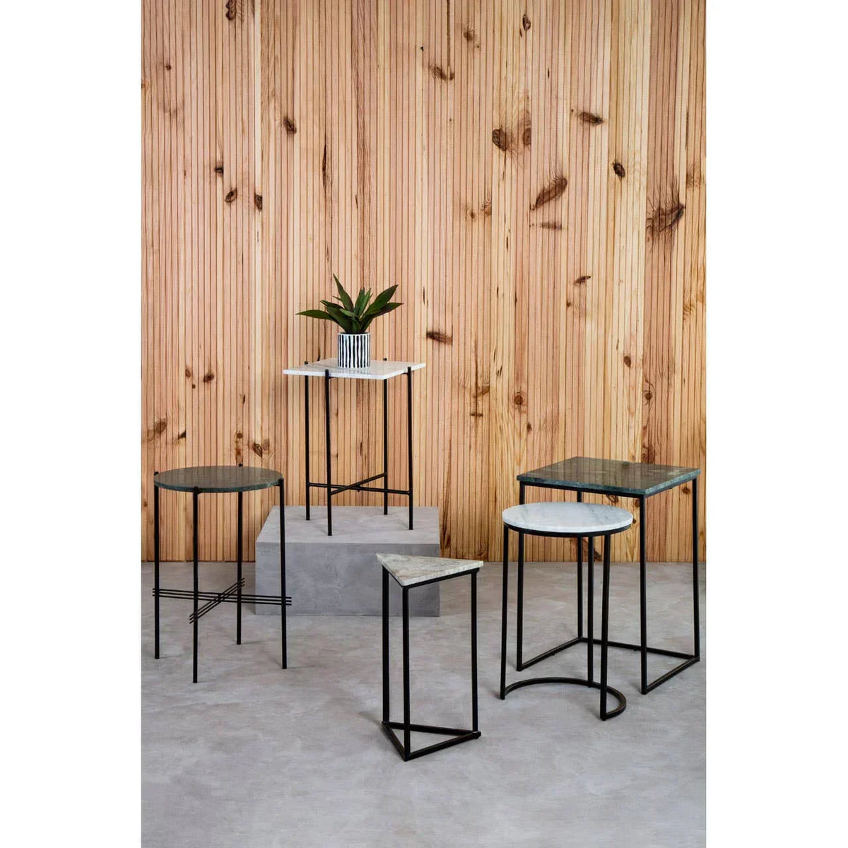 Set of marble top side tables with black metal frames against wooden panel wall