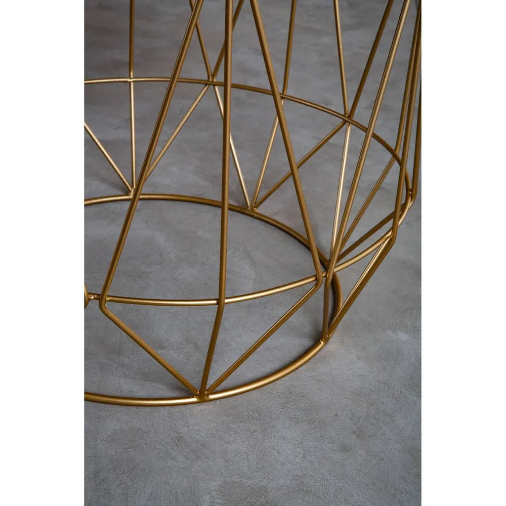 Gold metal table base with geometric frame on concrete floor