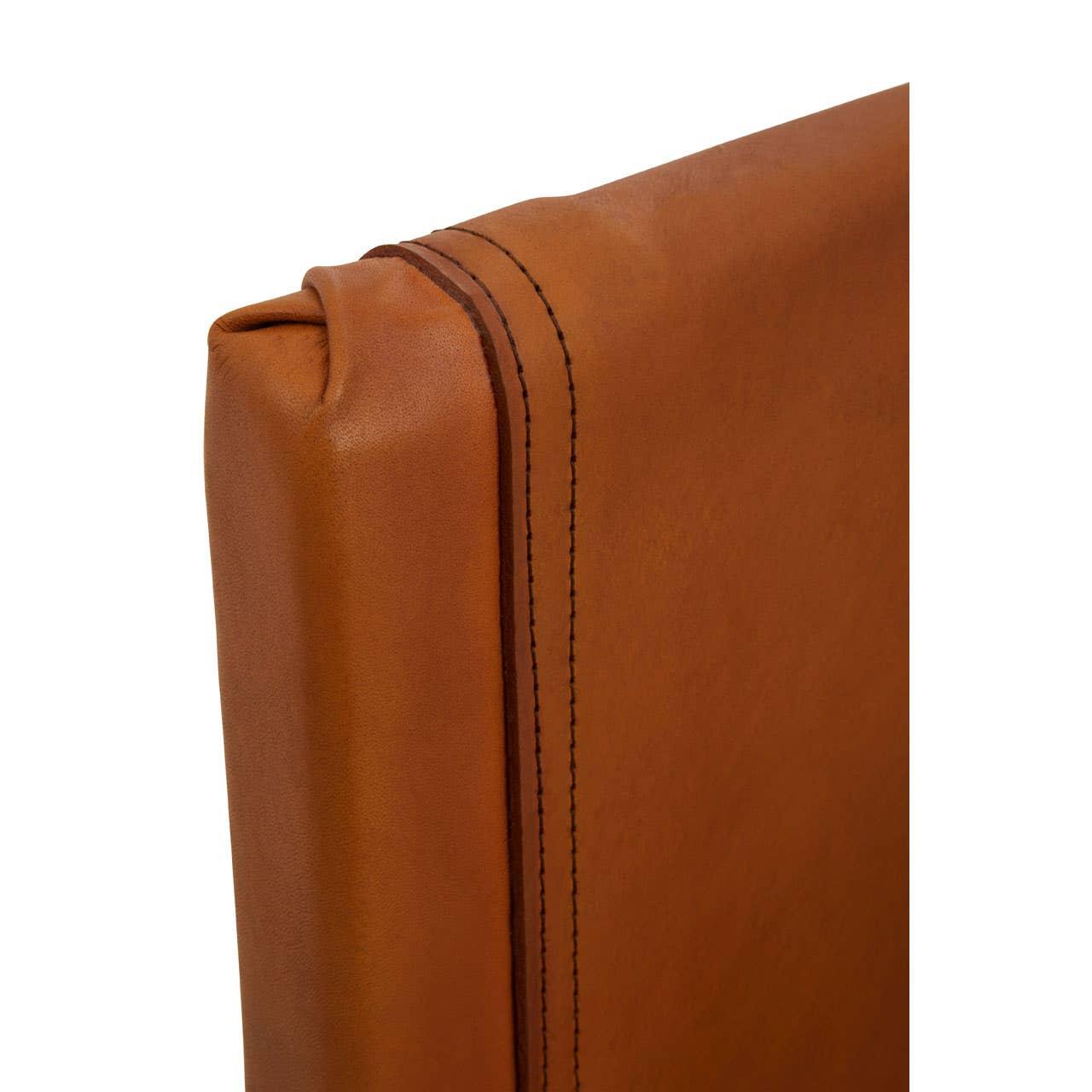 Tan leather chair back with visible stitching and smooth finish, close-up detail