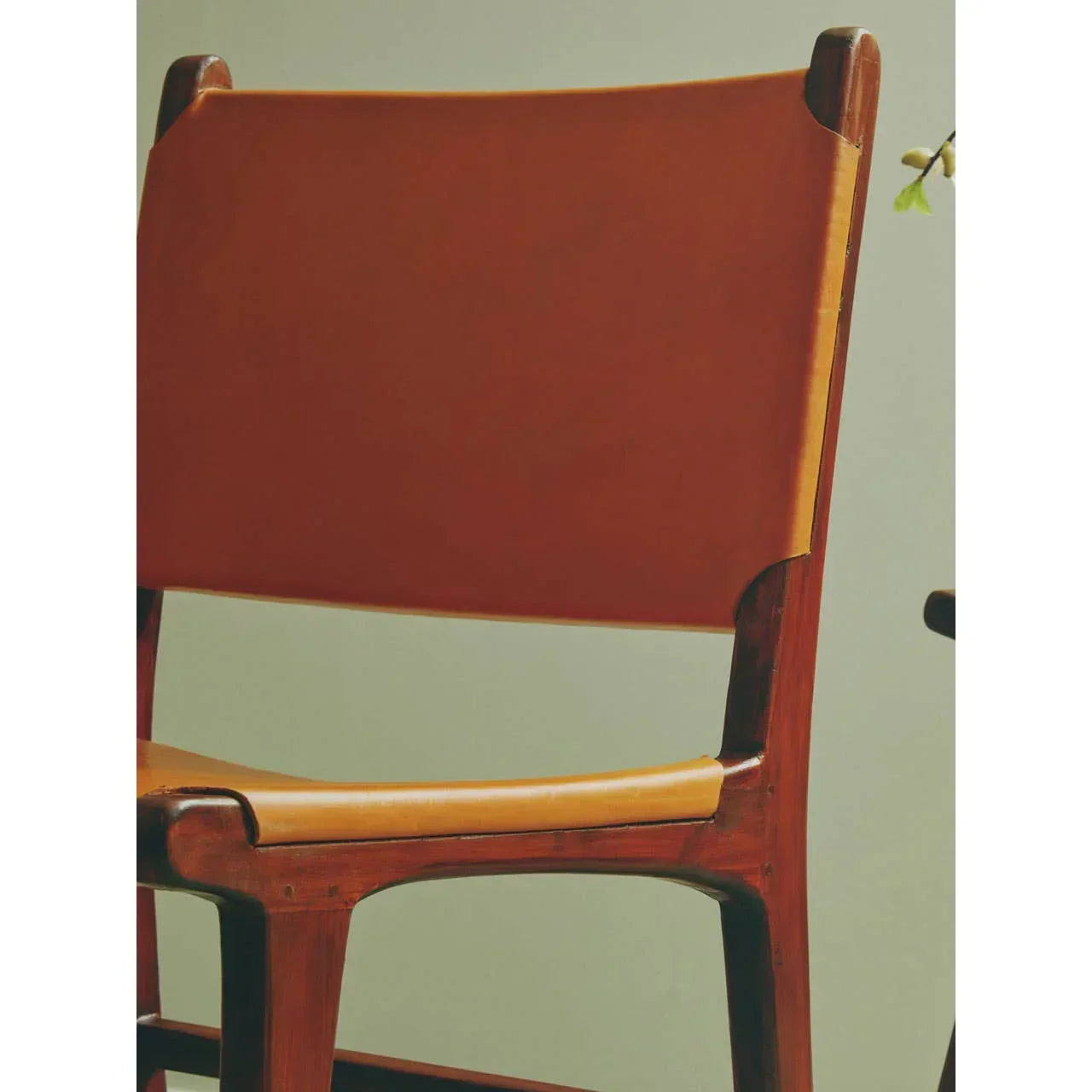 Mid-century modern dining chair with brown leather seat and wooden frame, side angle view