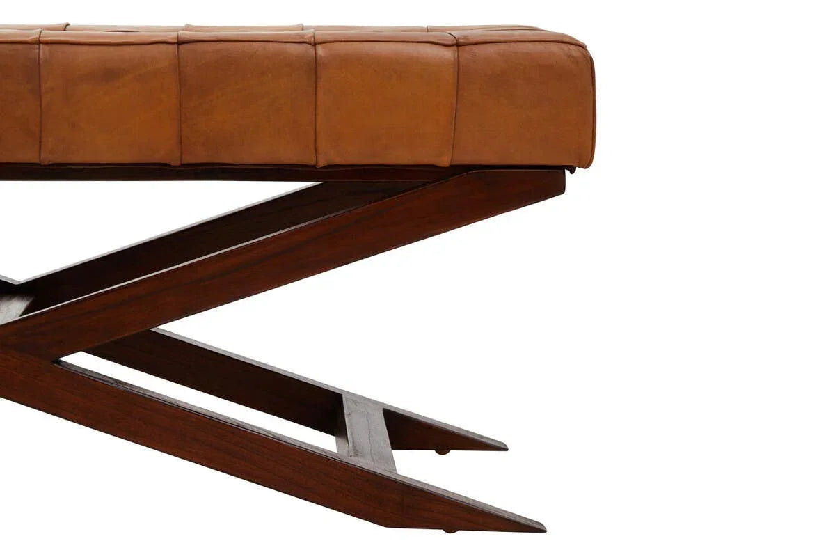 Tan leather bench seat with tufted cushion and dark wooden crossed legs, side view