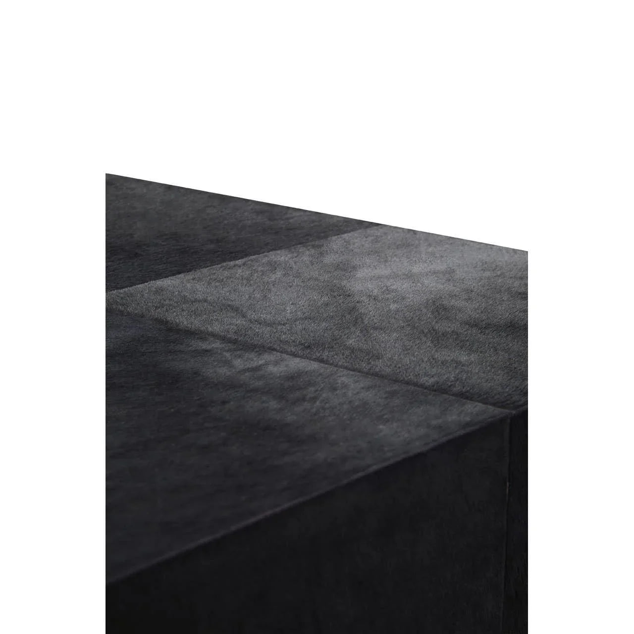 Closeup of black velvet ottoman corner showing textured fabric and seam detail