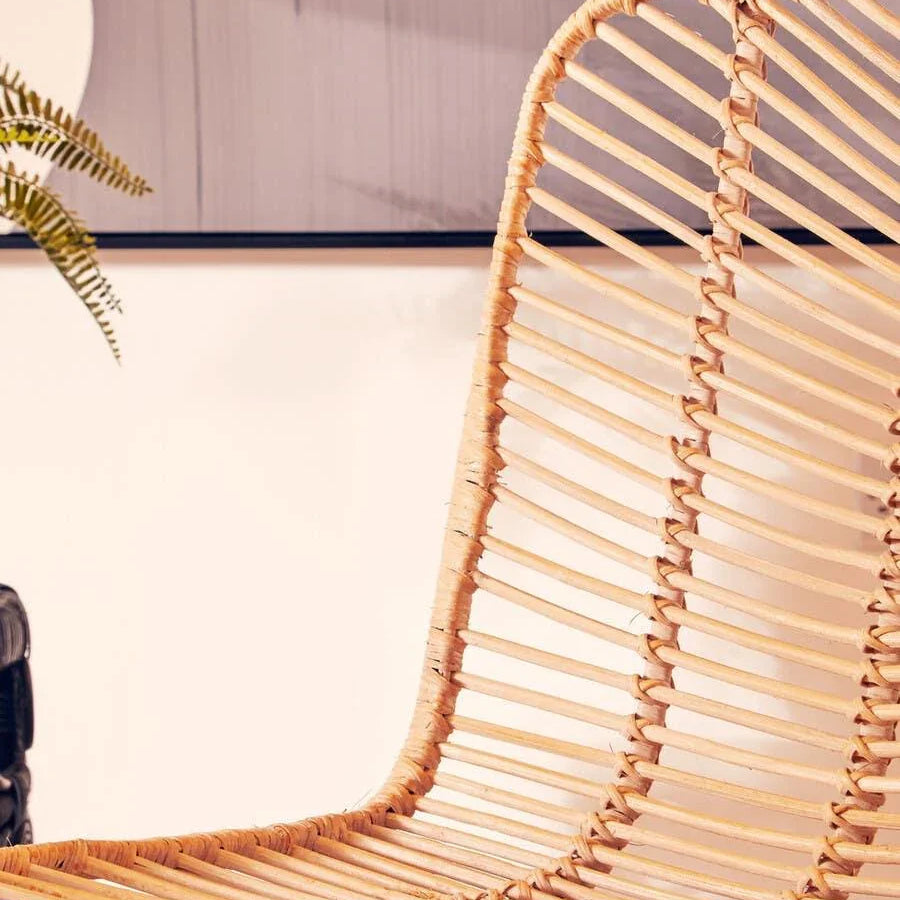 Close up of natural rattan dining chair with woven seat and curved backrest