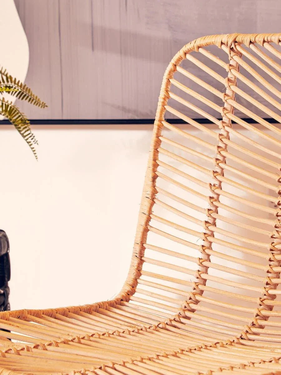 Close up of natural rattan dining chair with woven seat and curved backrest