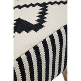 A close-up view of the Cefena Berber Style Footstool featuring a textured fabric with a geometric black and white pattern. The footstool has a soft, woven surface and is supported by wooden legs. The design includes zigzag and stripe motifs, adding a modern touch to a cozy aesthetic