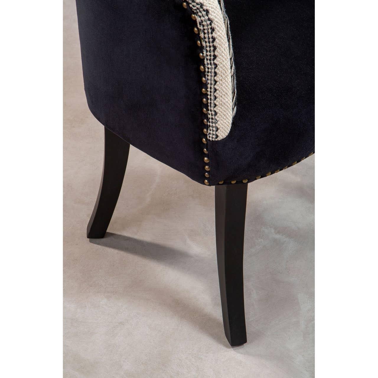 Navy velvet armchair with dark wood legs and brass stud detailing on side trim