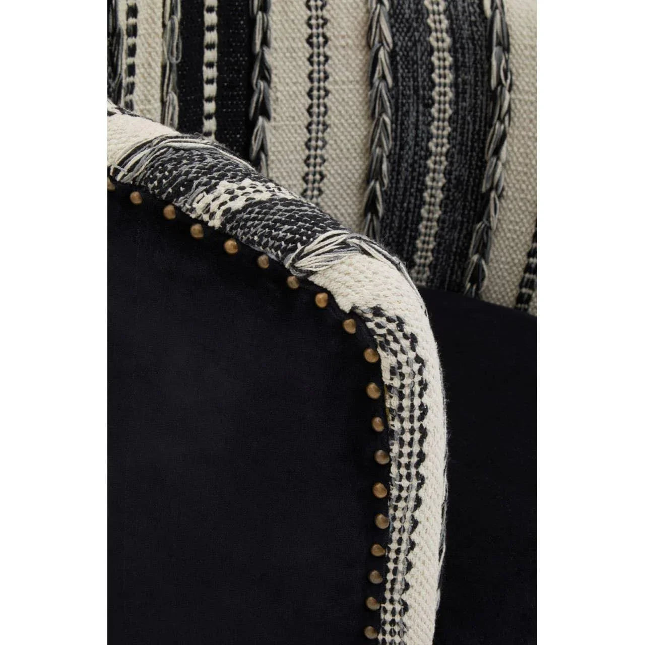 Black and cream woven fabric armchair closeup with brass stud detailing and textured upholstery