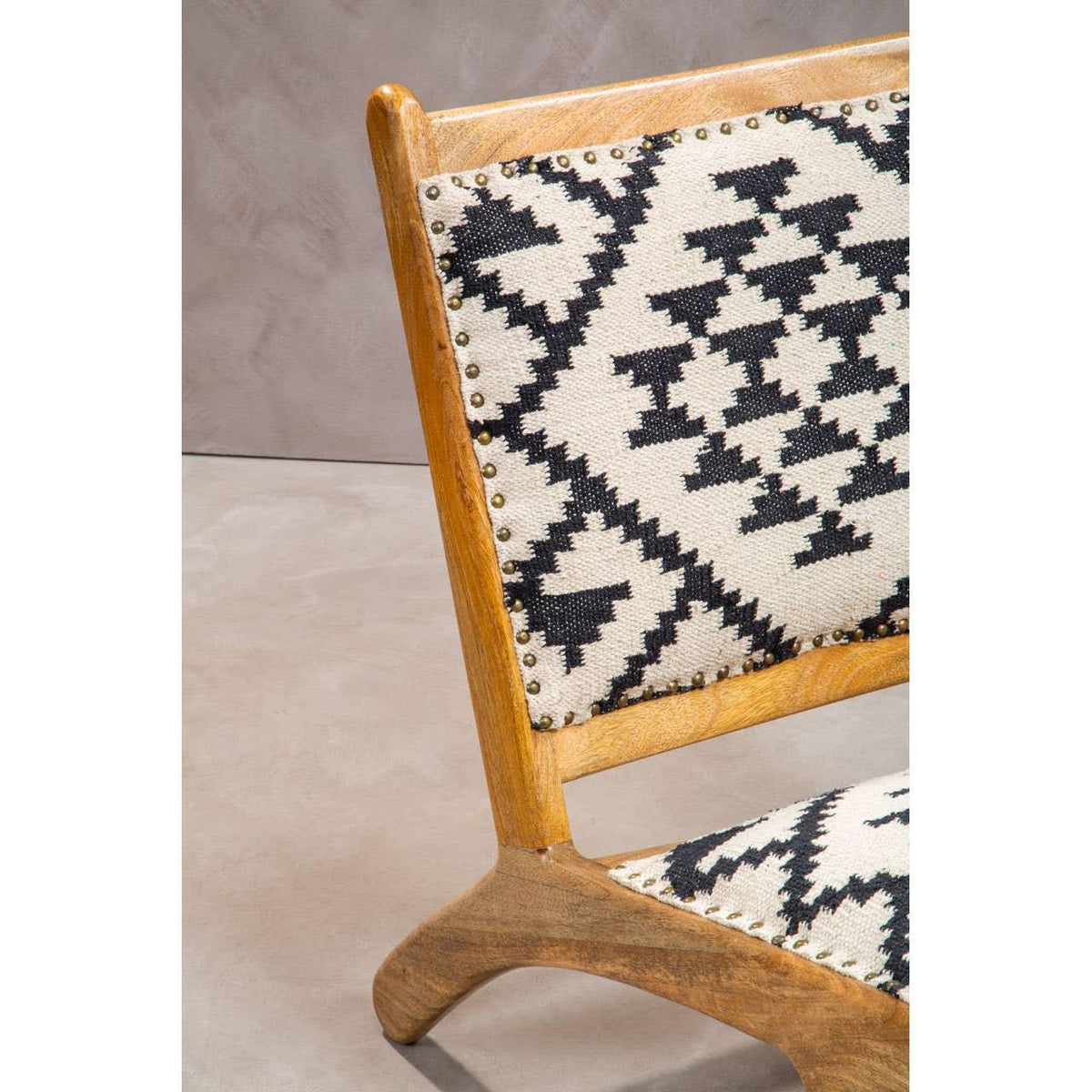 Wooden accent chair with black and white geometric upholstery and brass stud detailing