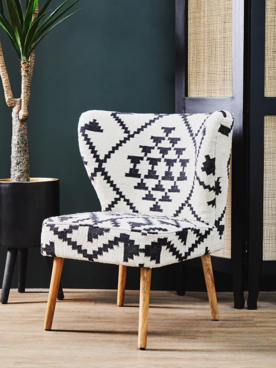 Black and white accent chair with geometric upholstery and wooden legs in a modern room
