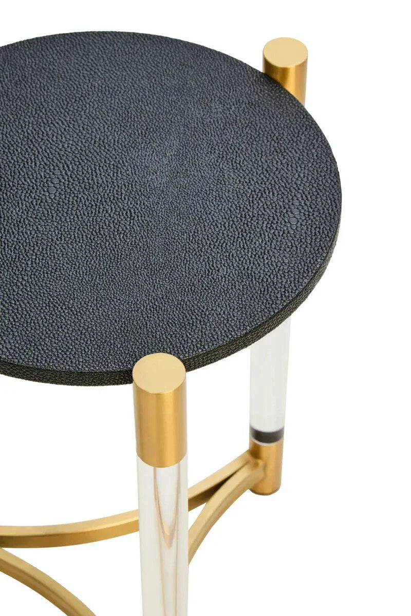 Round side table with textured black top, clear legs, and gold frame detailing