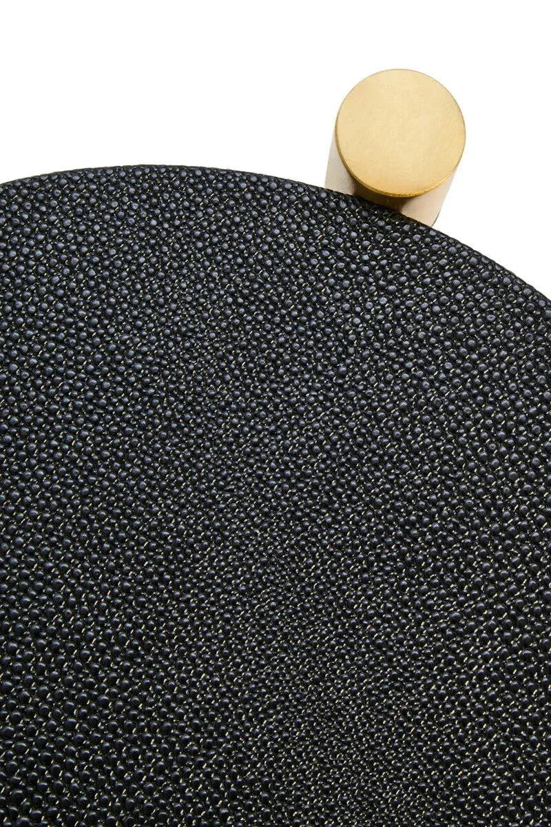 Close-up of black textured side table with gold metal accent