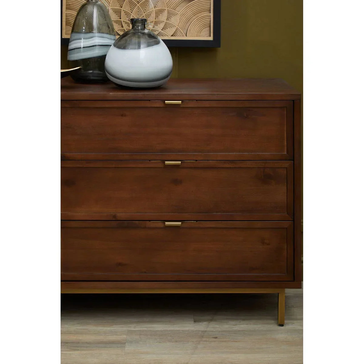 Walnut wood chest of drawers with gold handles and glass vases on top