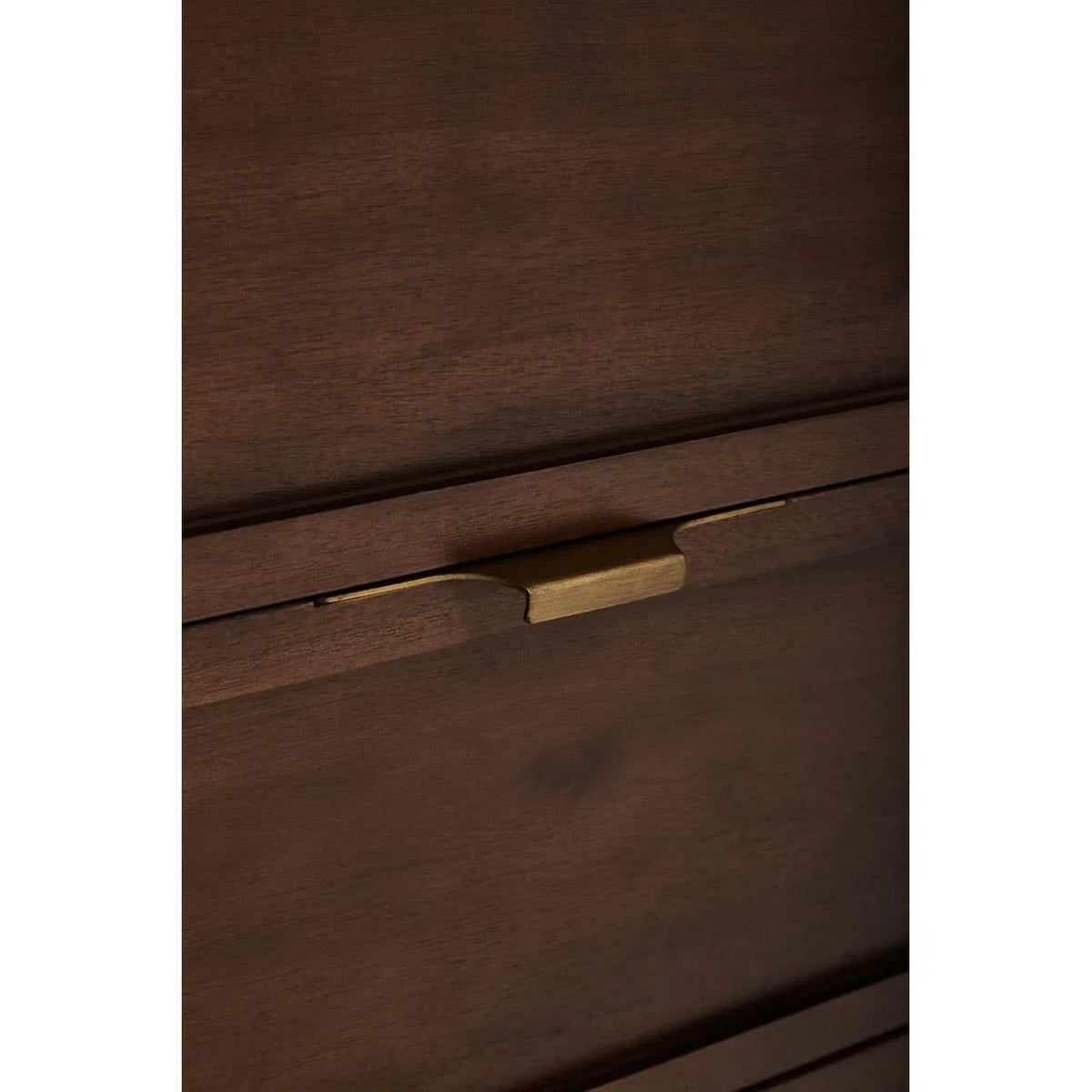 Walnut wood drawer front with brass handle, closeup of chest of drawers furniture