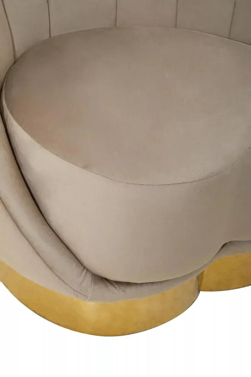 Beige velvet accent chair with curved seat cushion and gold metal base close-up