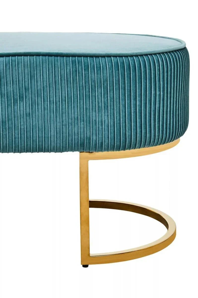 Blue velvet ottoman with vertical stitching and gold metal curved base, side view