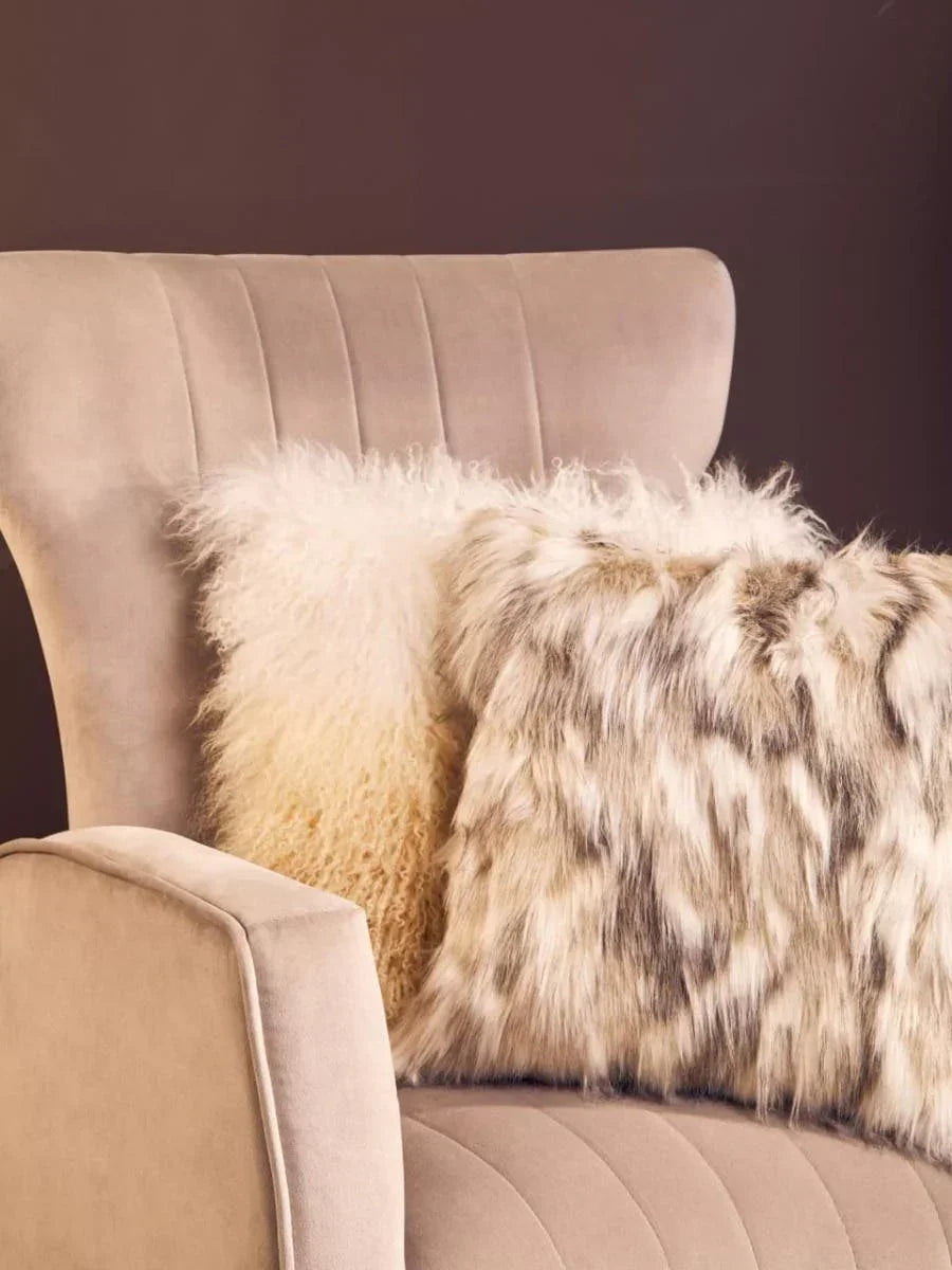 Beige velvet armchair with two faux fur cushions in a neutral living room setting